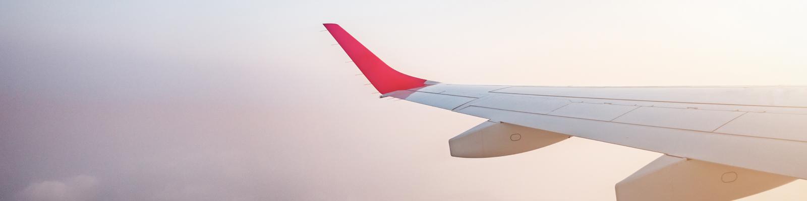 Plane wing is photographed amidst a sunset.