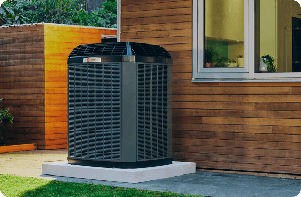 There is a Trane home air conditioner is outside of a residential home.