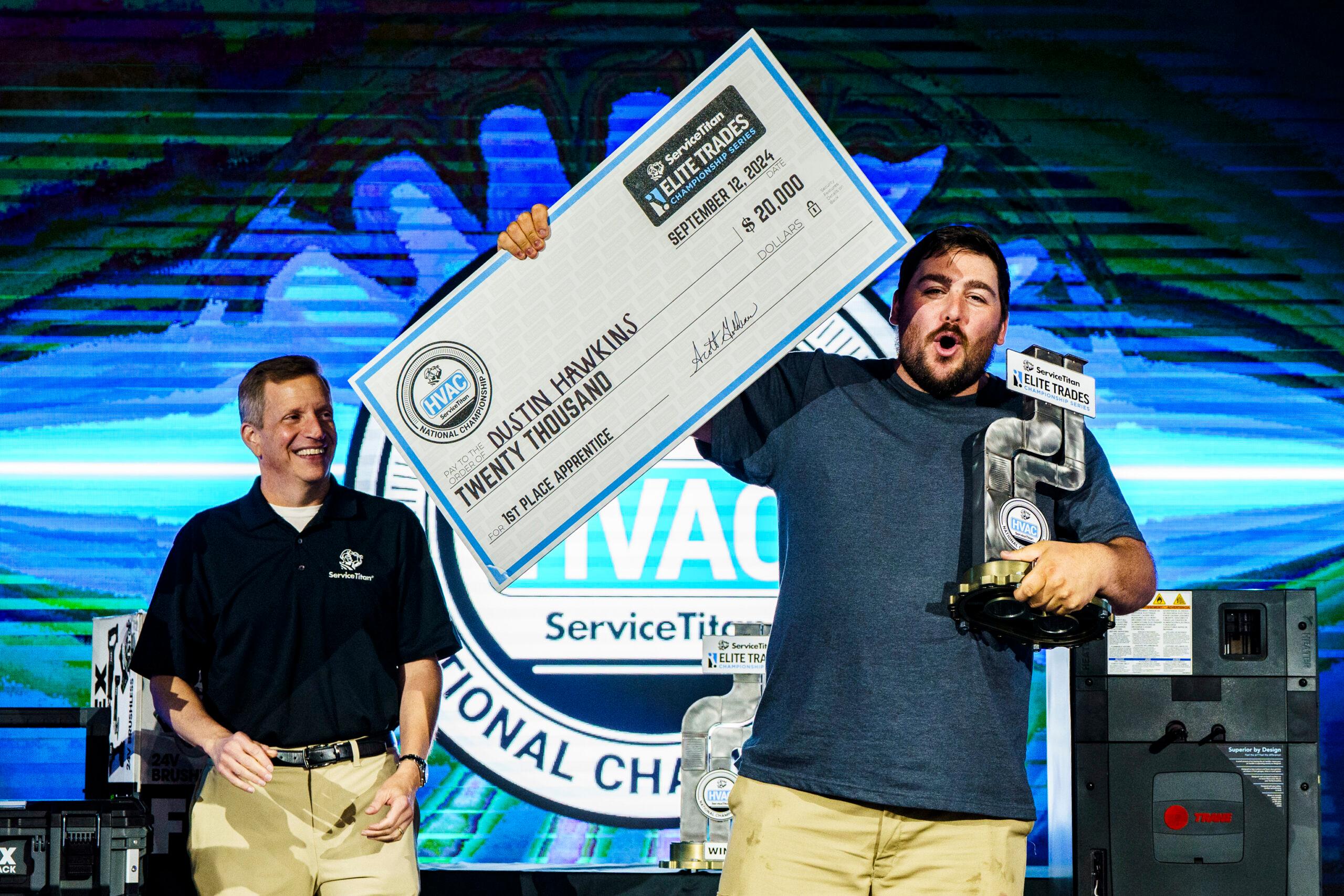 A competition winner stands on stage as he's presented with a large prize check.