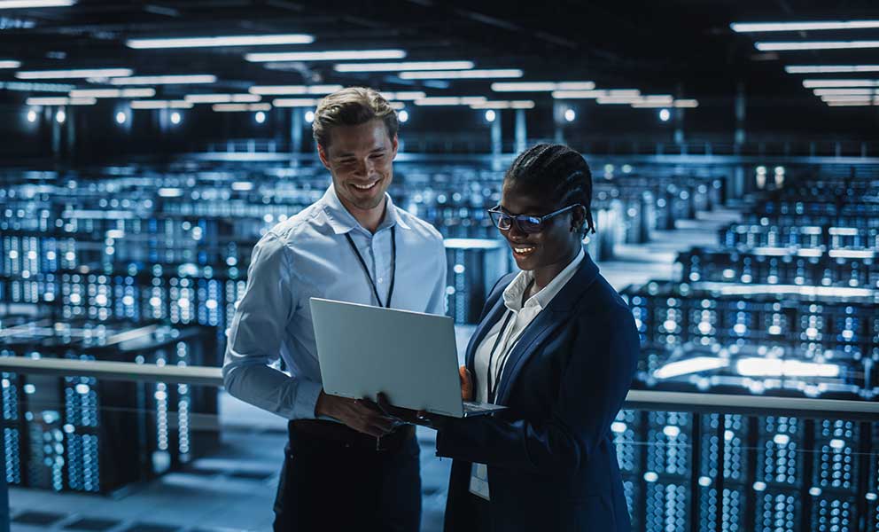Data Center Female System Administrator and Male IT Specialist talk, Use Laptop. Information Technology Engineers work on Cyber Security Protection in Cloud Computing Server Farm.